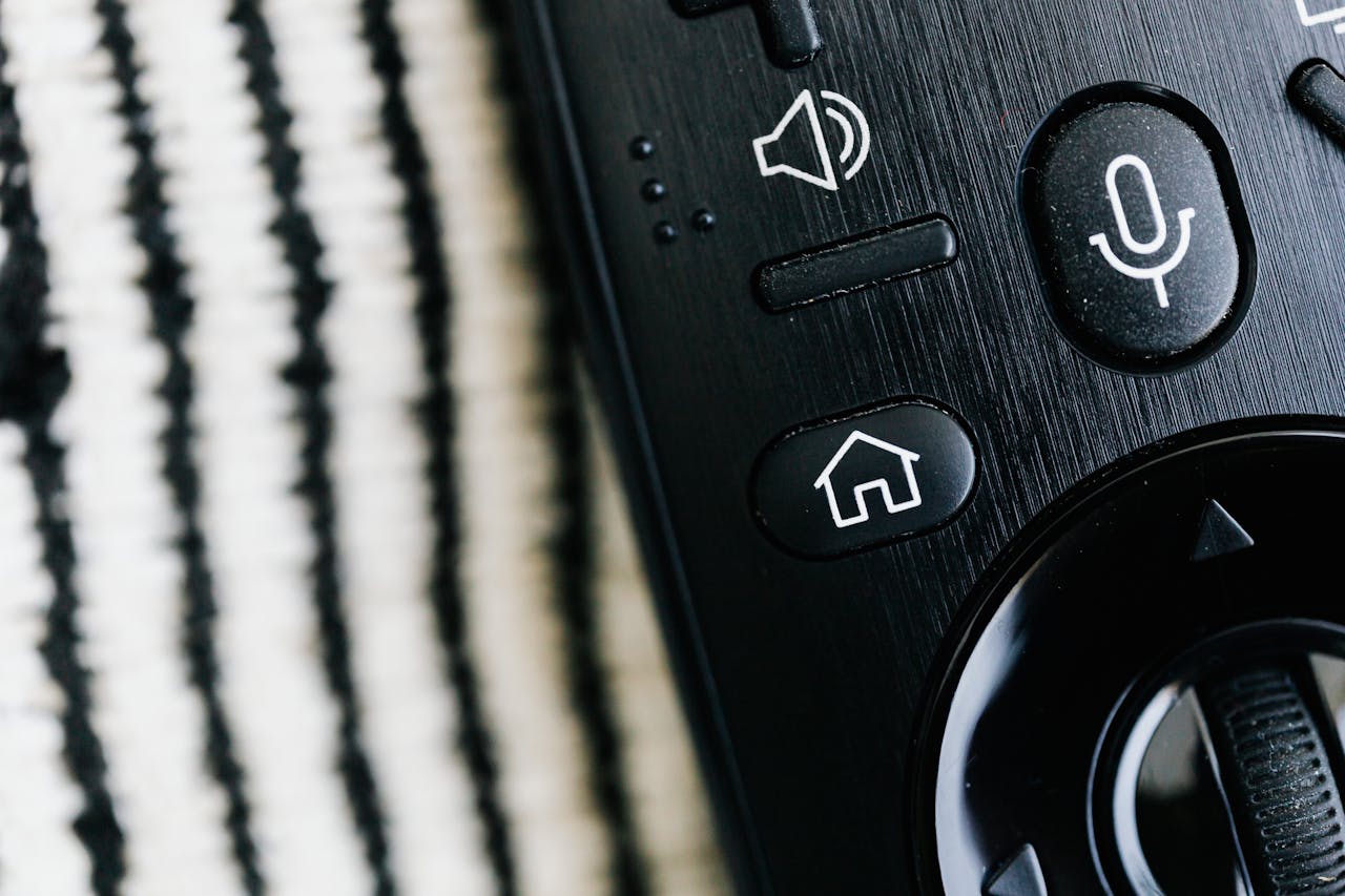 Detailed macro shot of a sleek black remote control with microphone button and textured background.