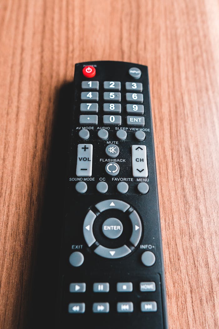 High angle of remote control with numbers and symbols on buttons on brown background in shiny light